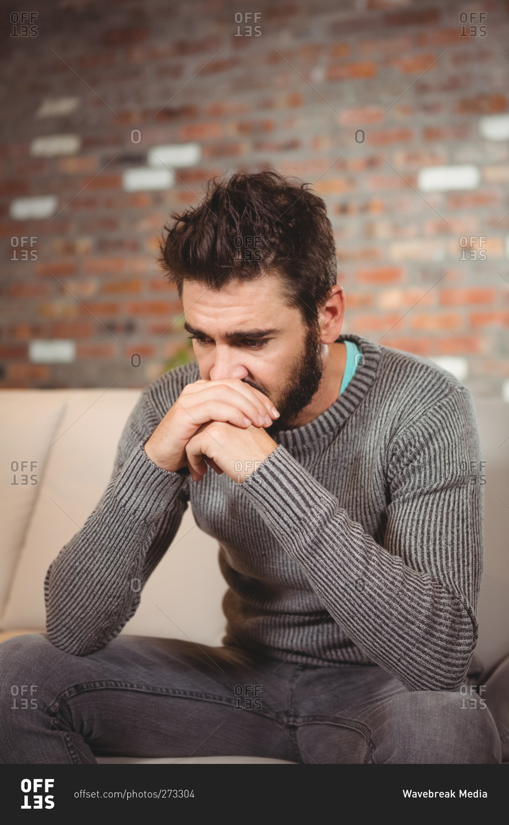Stressed man with hands in front of mouth at home
