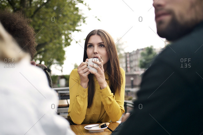 Woman enjoying coffee with friends at outdoor cafe