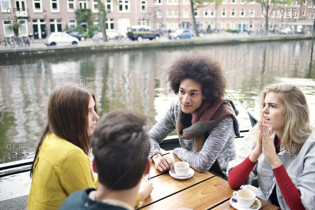Four friends seated at cafe along canal in Amsterdam