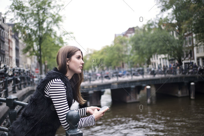 Woman leans on railing over canal in Amsterdam