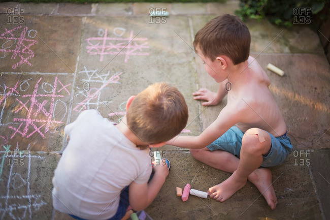 Overhead view of boys drawing on walkway with chalk