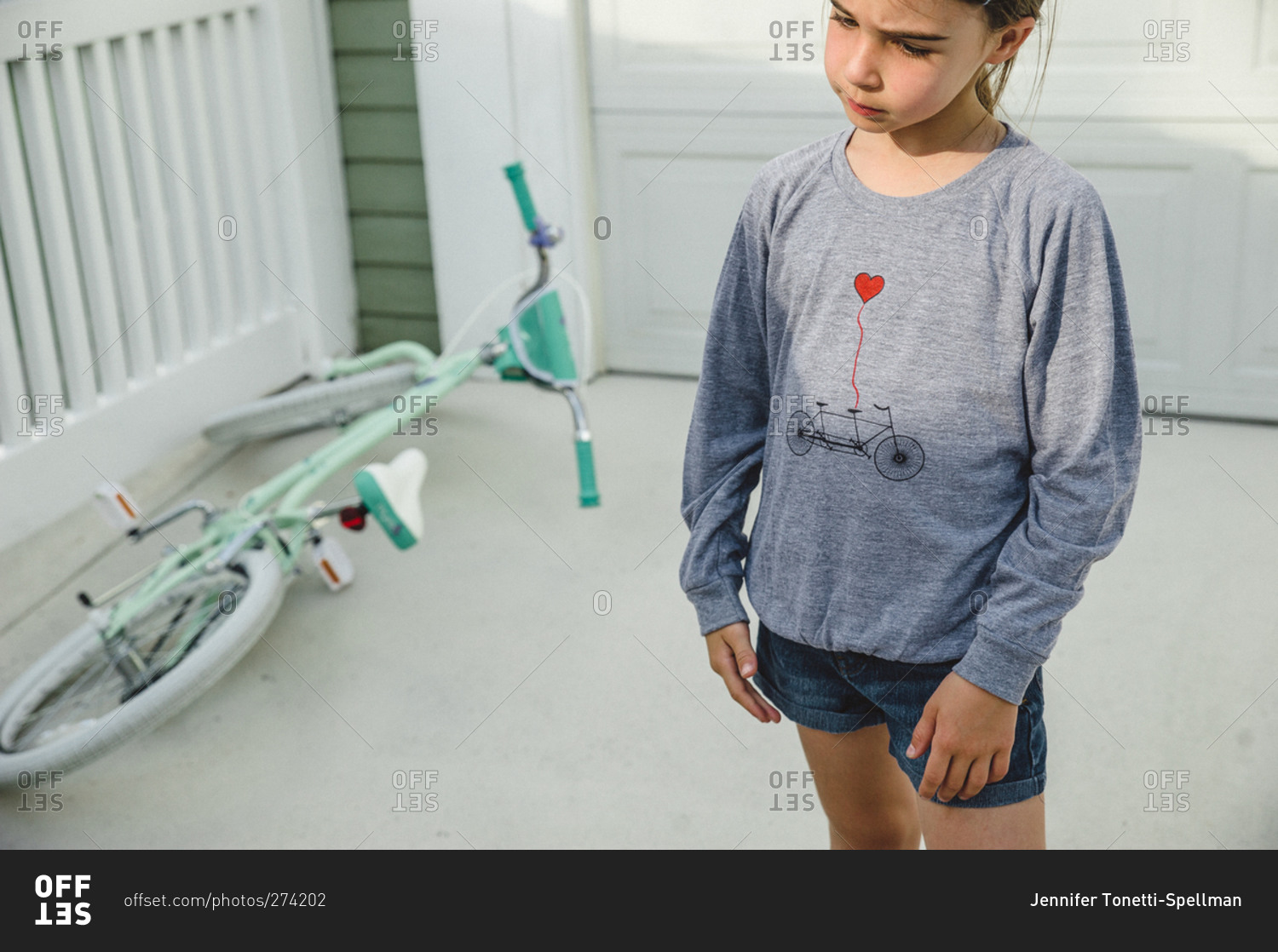 Sad looking girl standing next to her bike