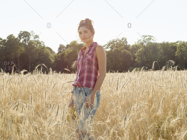 Young woman wearing a checkered shirt standing in a wheat field