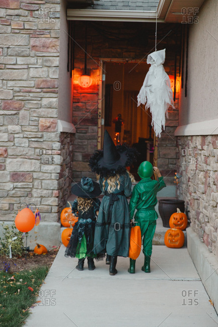 Three kids in costumes at a front door