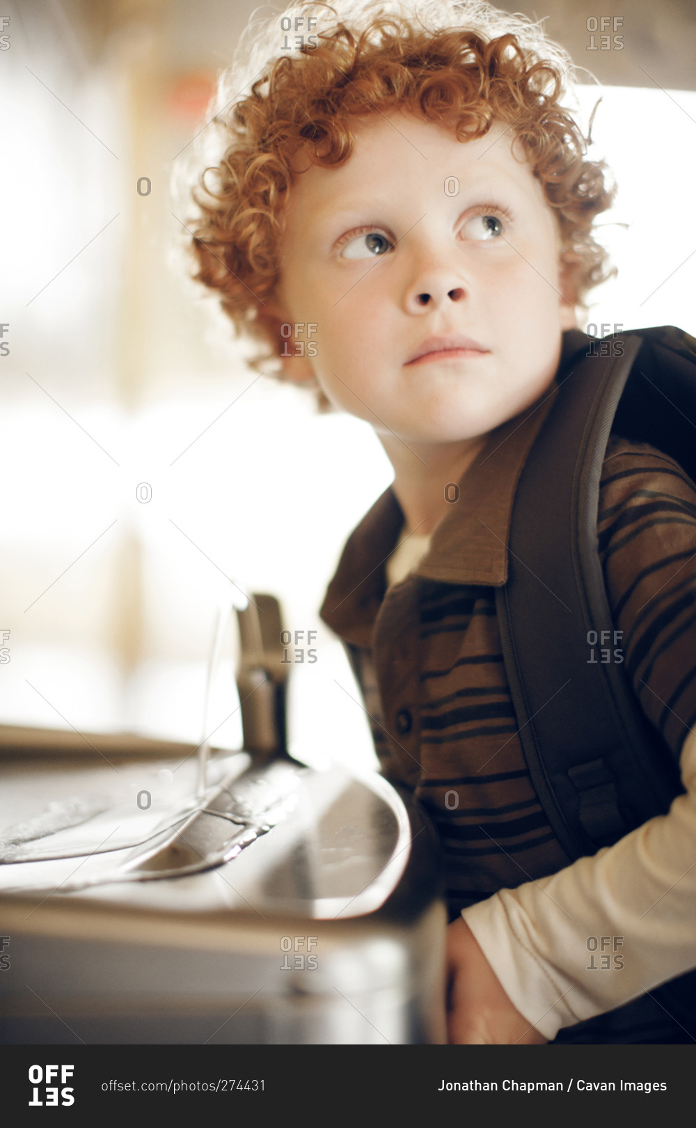 Boy wearing backpack at school water fountain