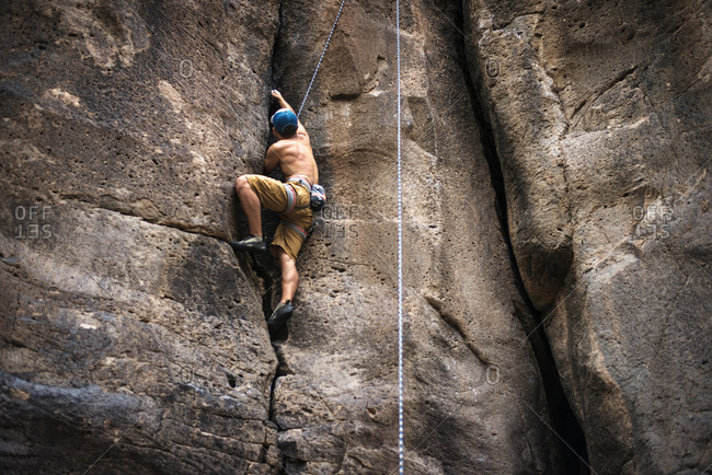 Man finding grip climbing up rock face