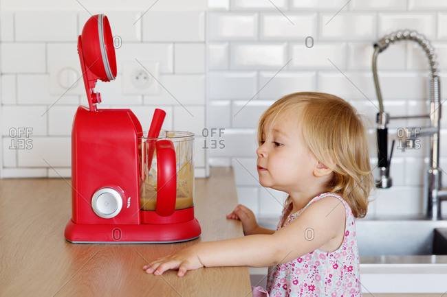 Little girl looking at homemade applesauce in a blender