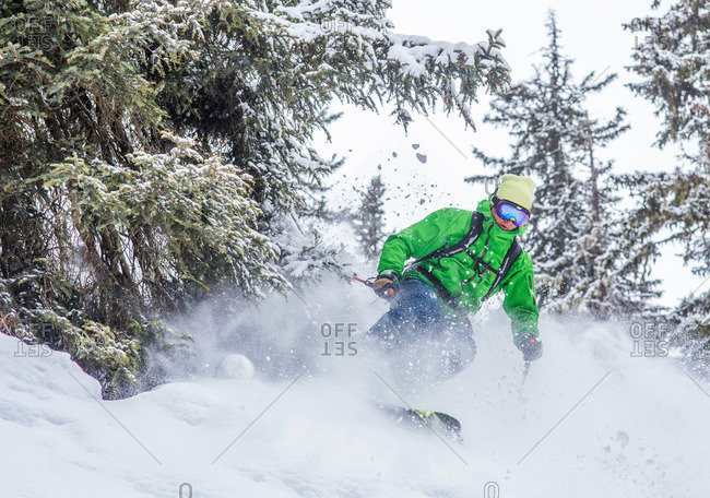 Man skiing on powder snow through trees - Stock Image - Everypixel