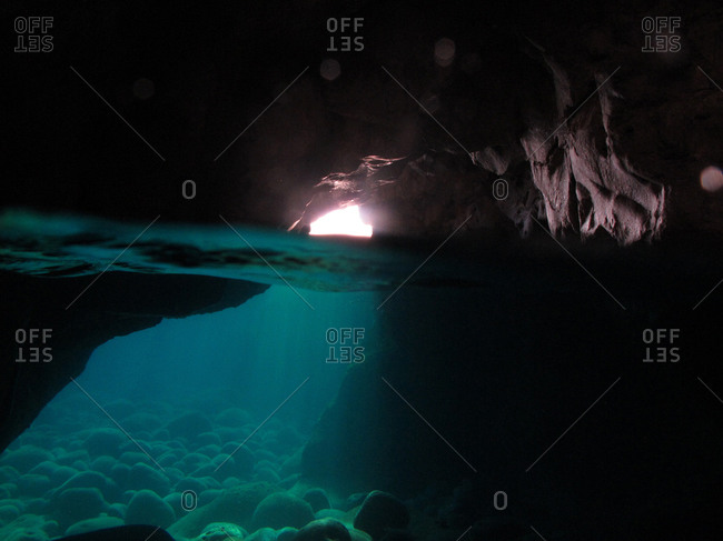 Light shining from a cave opening into an underwater cave