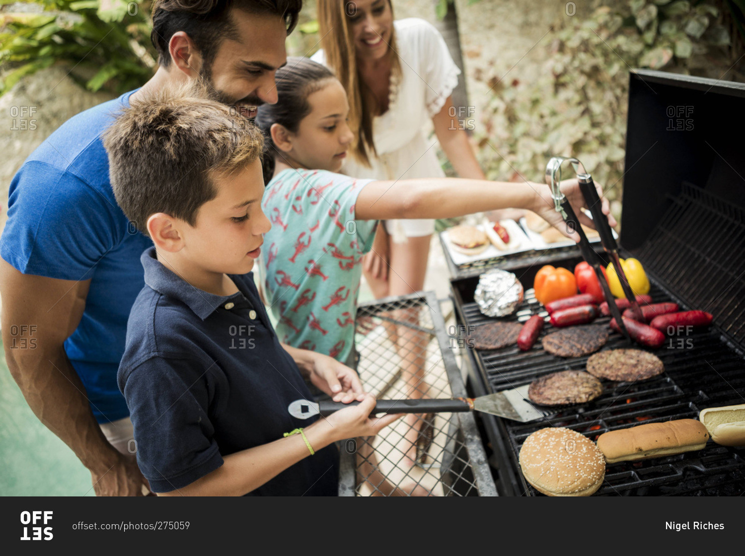 Family grilling burgers and hot dogs together