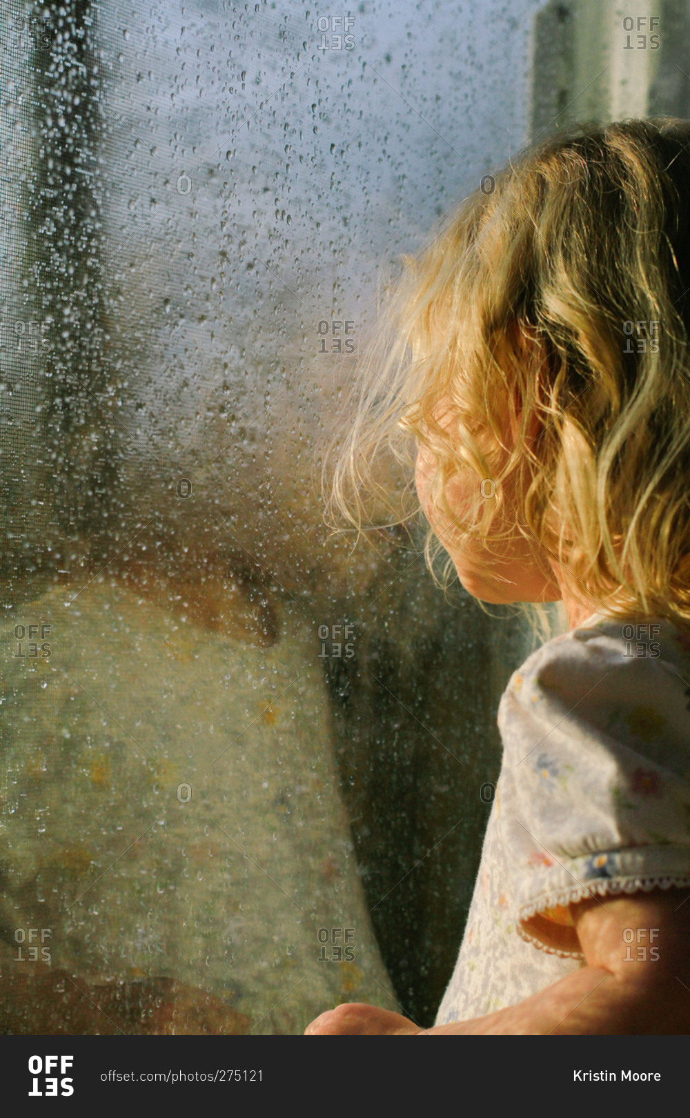 Girl peering out window while it rains