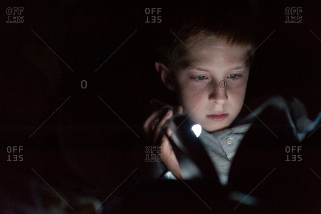Boy using a flashlight to read