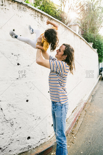 Man playfully swings his young child up in the air