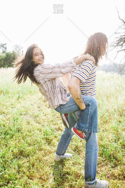 Man giving woman a piggy back ride in a field