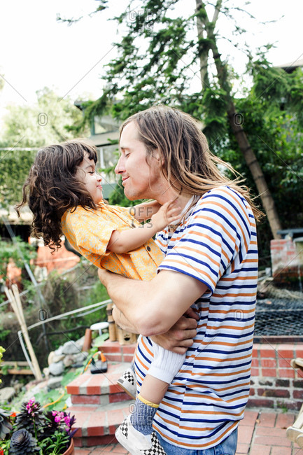 Child leans away from father as he playfully tries to give a kiss