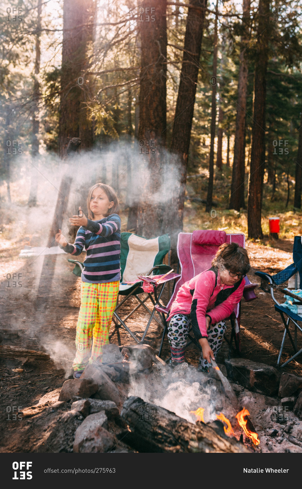 Two kids playing with smoke of campfire