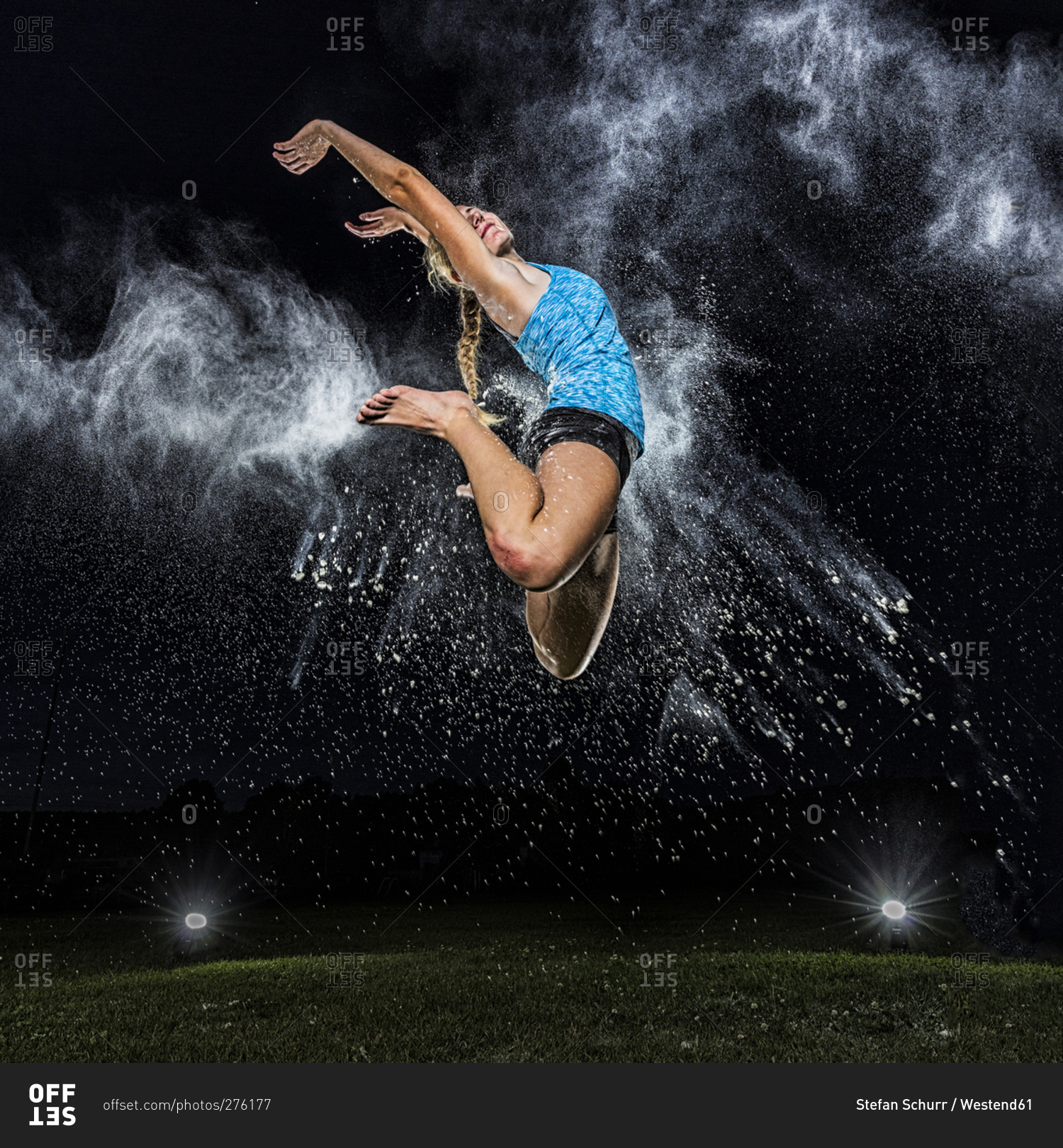 Young woman jumping in the air in between cloud of flour