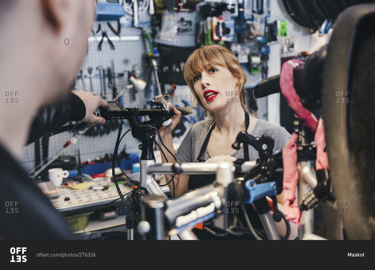 Female mechanic talking to customer in a bicycle repair shop