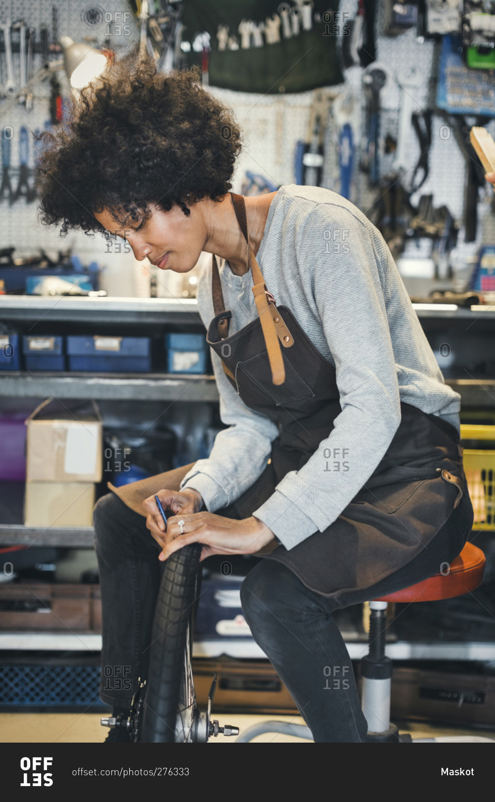 Mid adult female mechanic repairing bicycle tire in a workshop