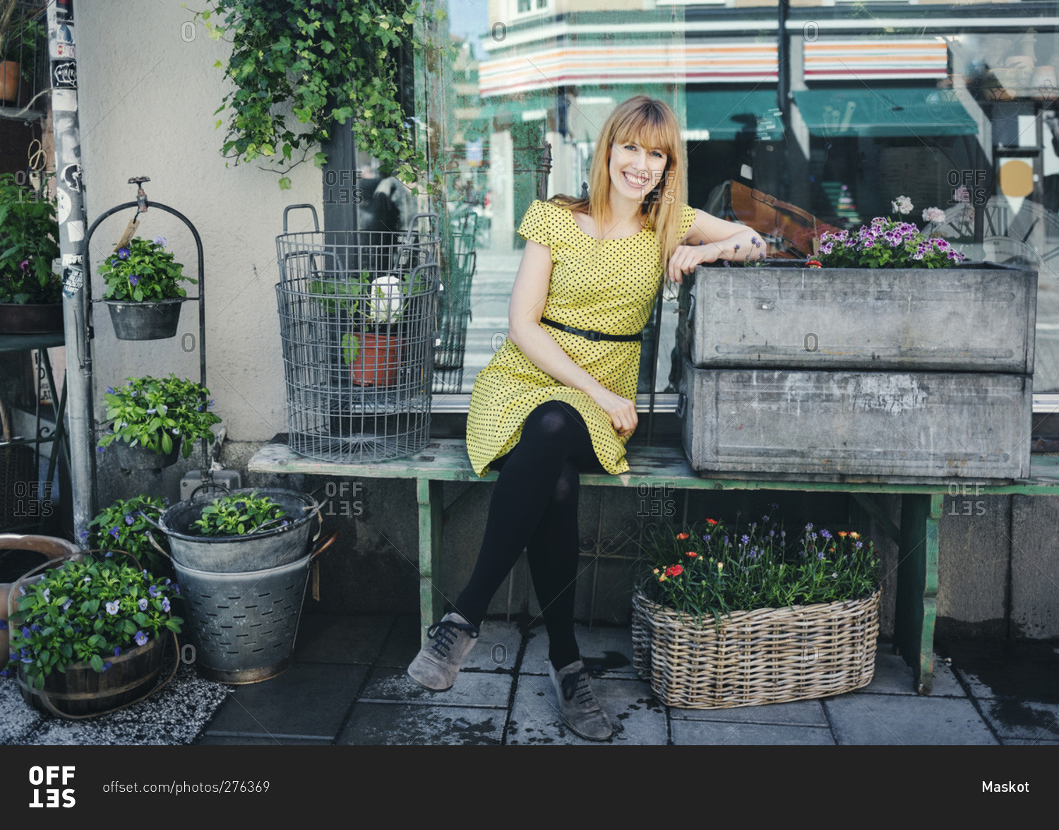 Portrait of happy owner leaning on crate outside plant shop