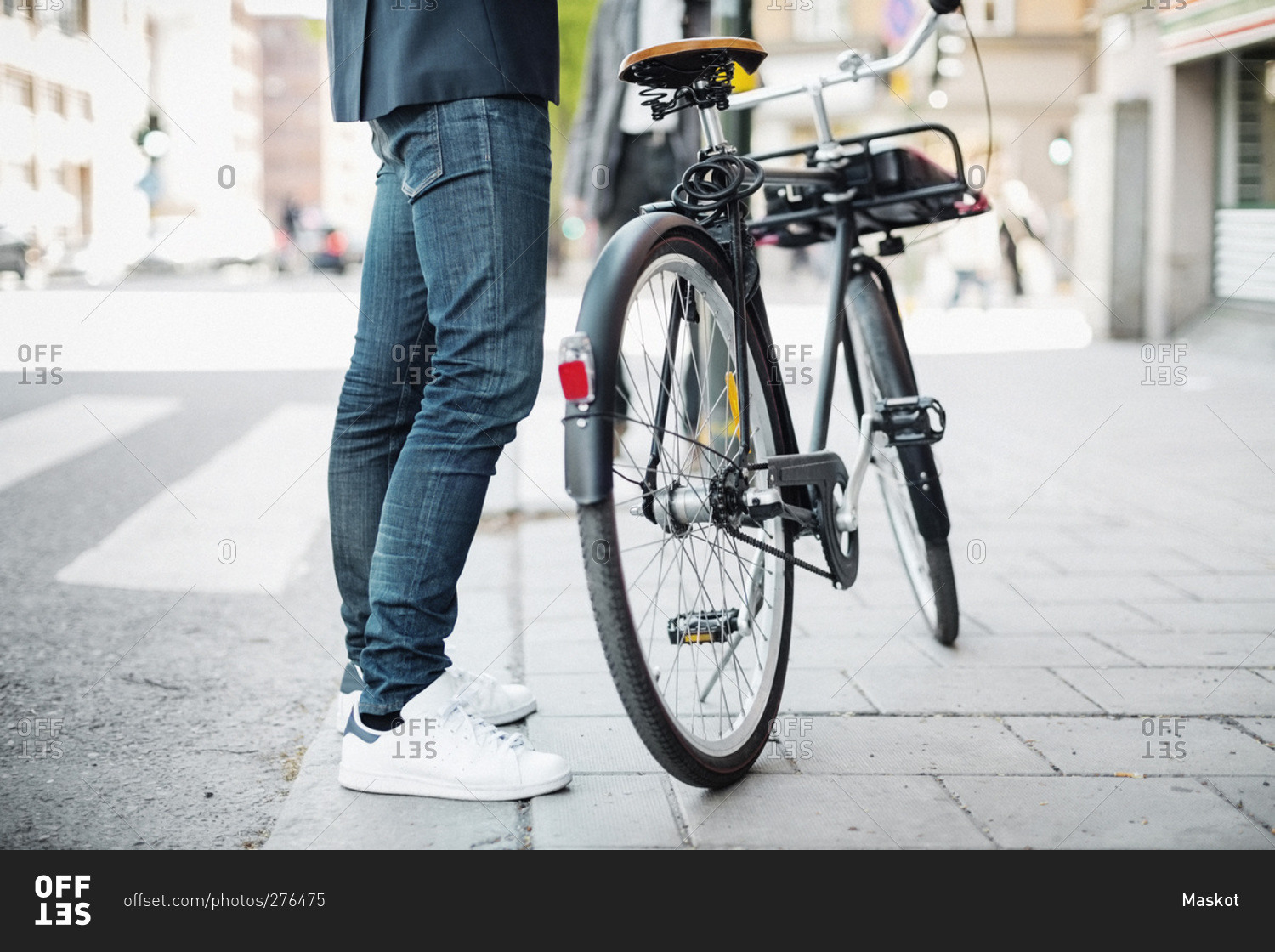 Low section of businessman standing with bicycle on city street