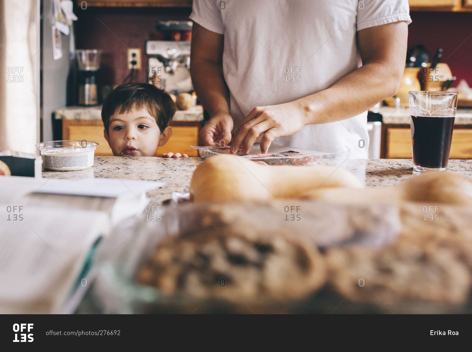 Child peers over counter while man preps Thanksgiving food
