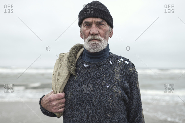 Senior man in a woolen sweater standing on a beach