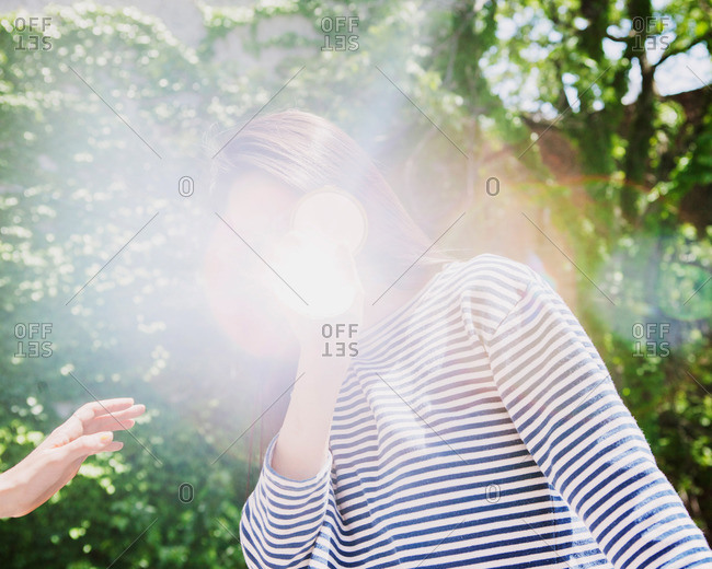 Hand reaching for woman whose face is obscured by a lens flare