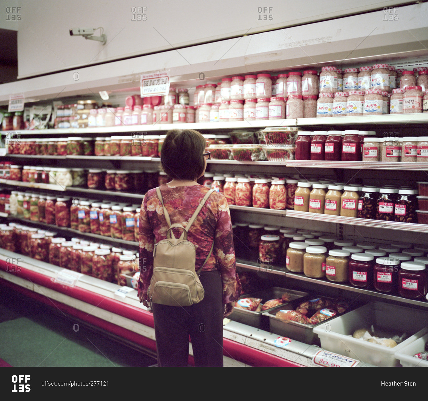 Woman looking at jars of food in refrigerated case of market