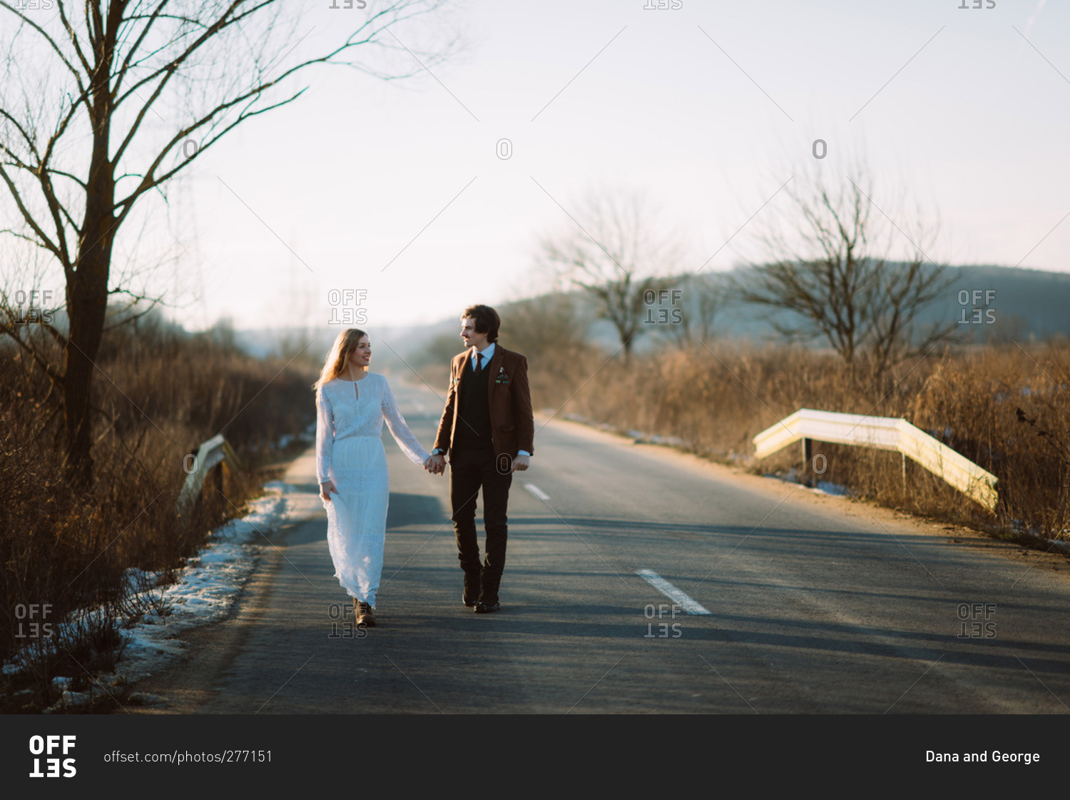 Stylish bride and groom walking down road