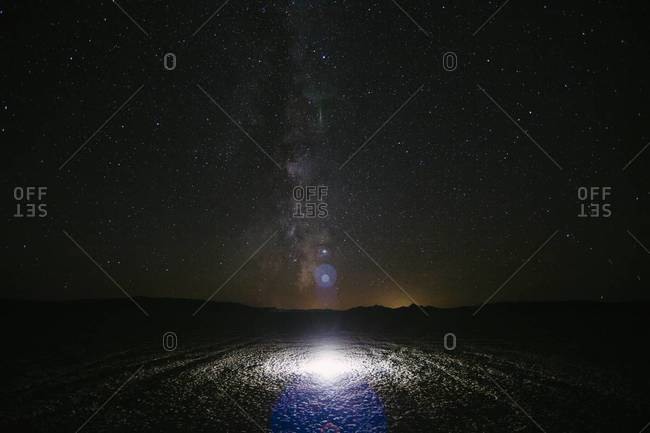 View of Milky Way and night sky, bright glowing light on surface of playa in foreground, Black Rock Desert, Nevada, USA