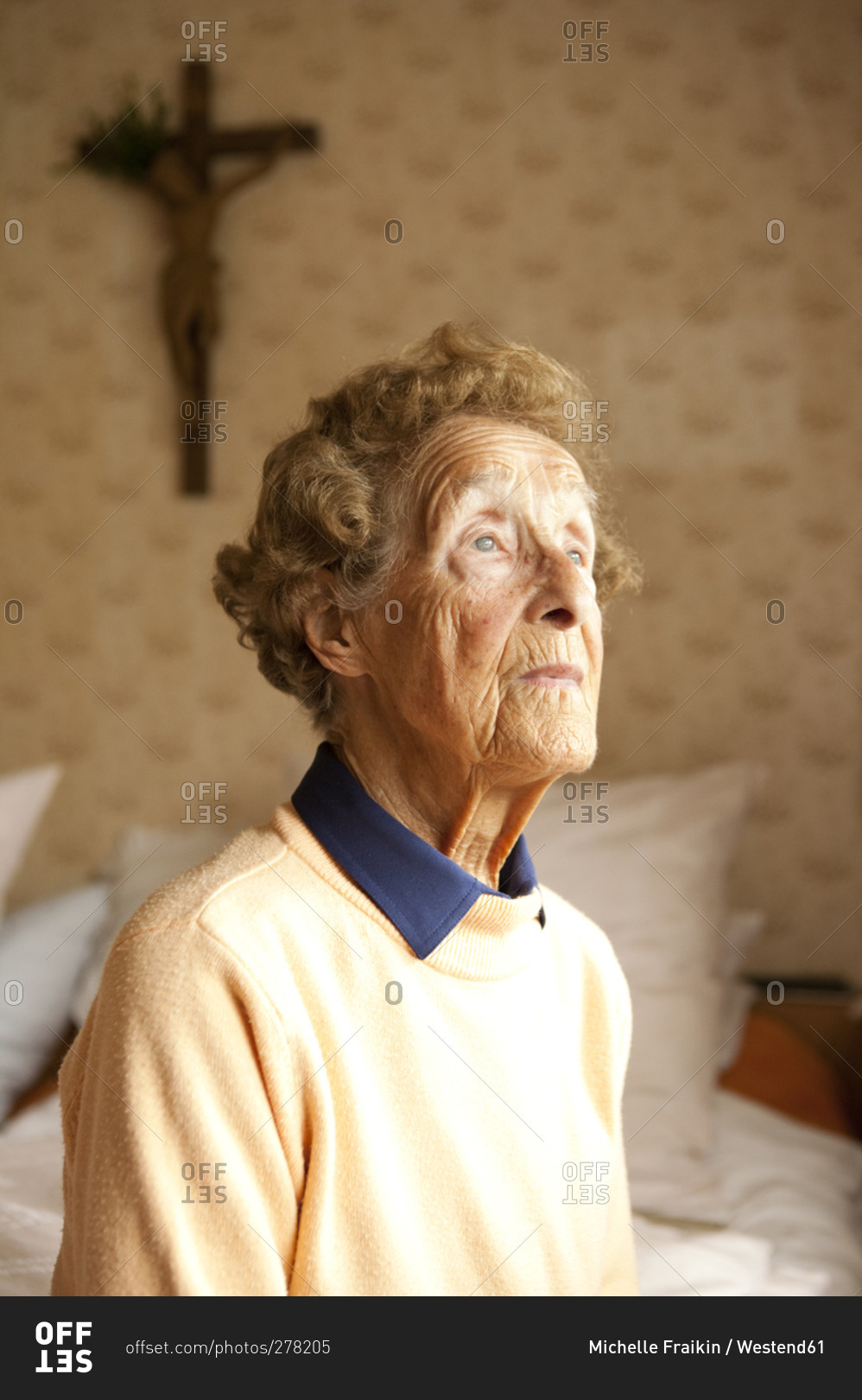 Portrait of aged woman sitting on bed in her bedroom