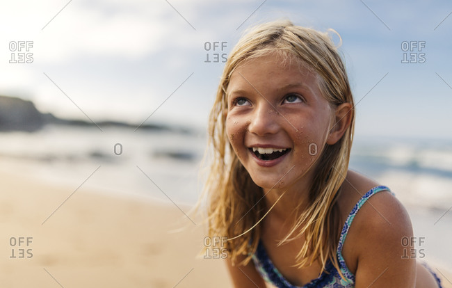 Portrait of smiling little girl running on beach stock photo - OFFSET