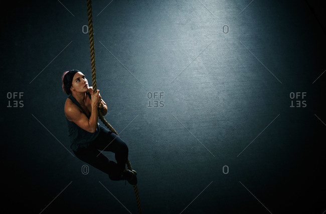 Woman climbing a rope during crossfit training