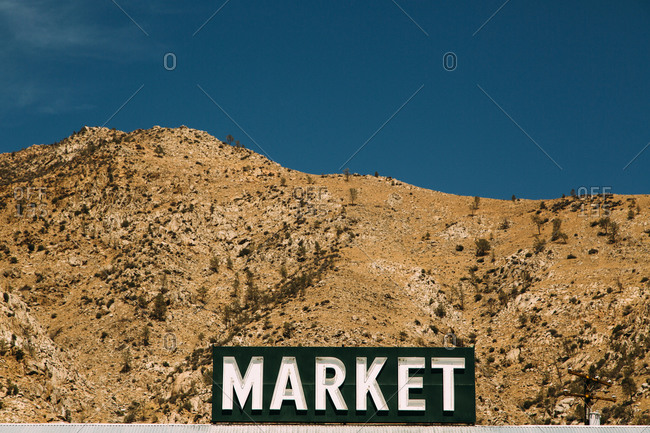 Sign for a market in front of arid mountainous terrain