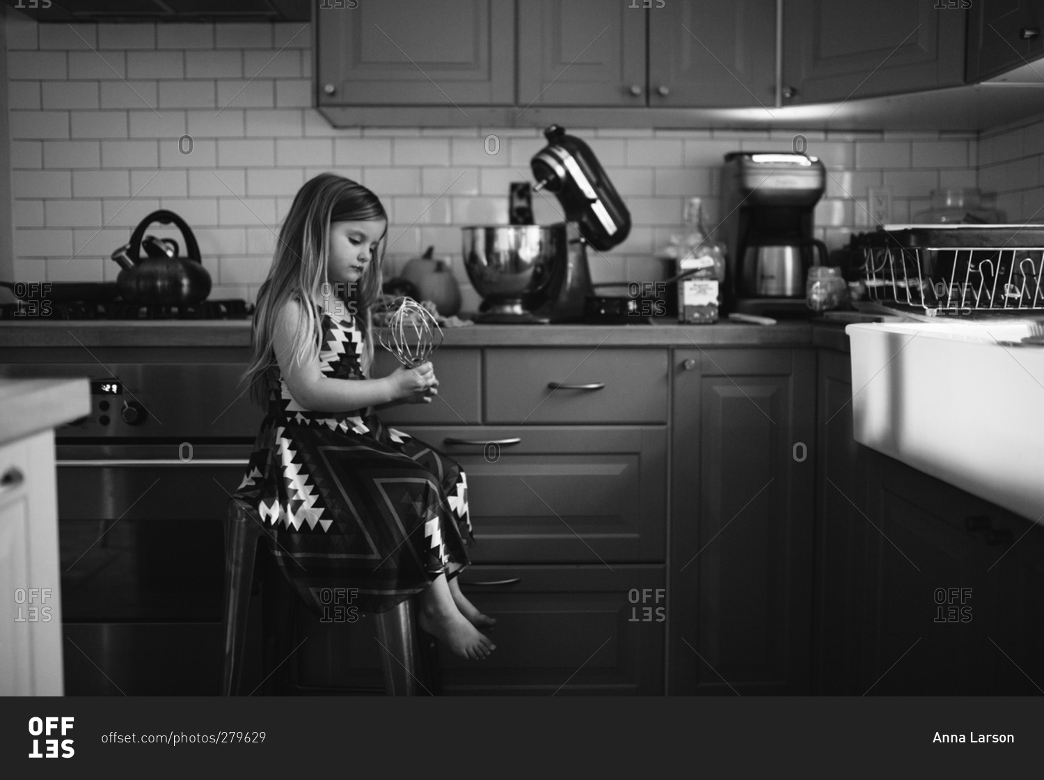 Black and white of little girl ready to bake in the kitchen