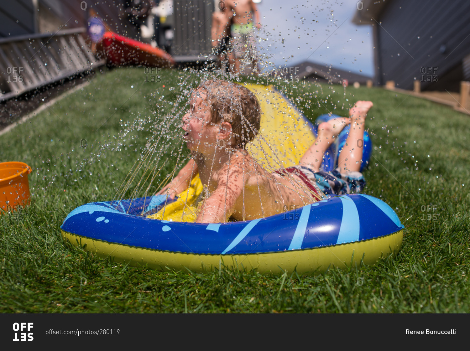 Boy reaching bottom of water slide sheet