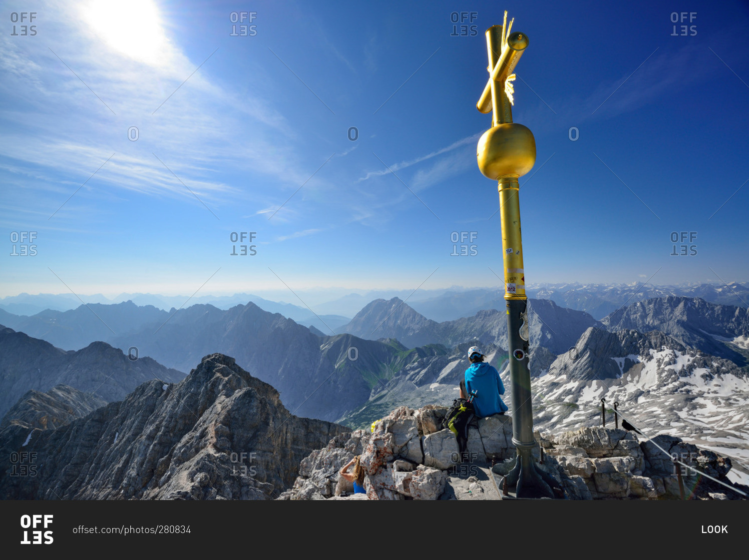 Person sitting beside summit cross of mount Zugspitze, Wetterstein mountain range, Upper Bavaria, Bavaria, Germany