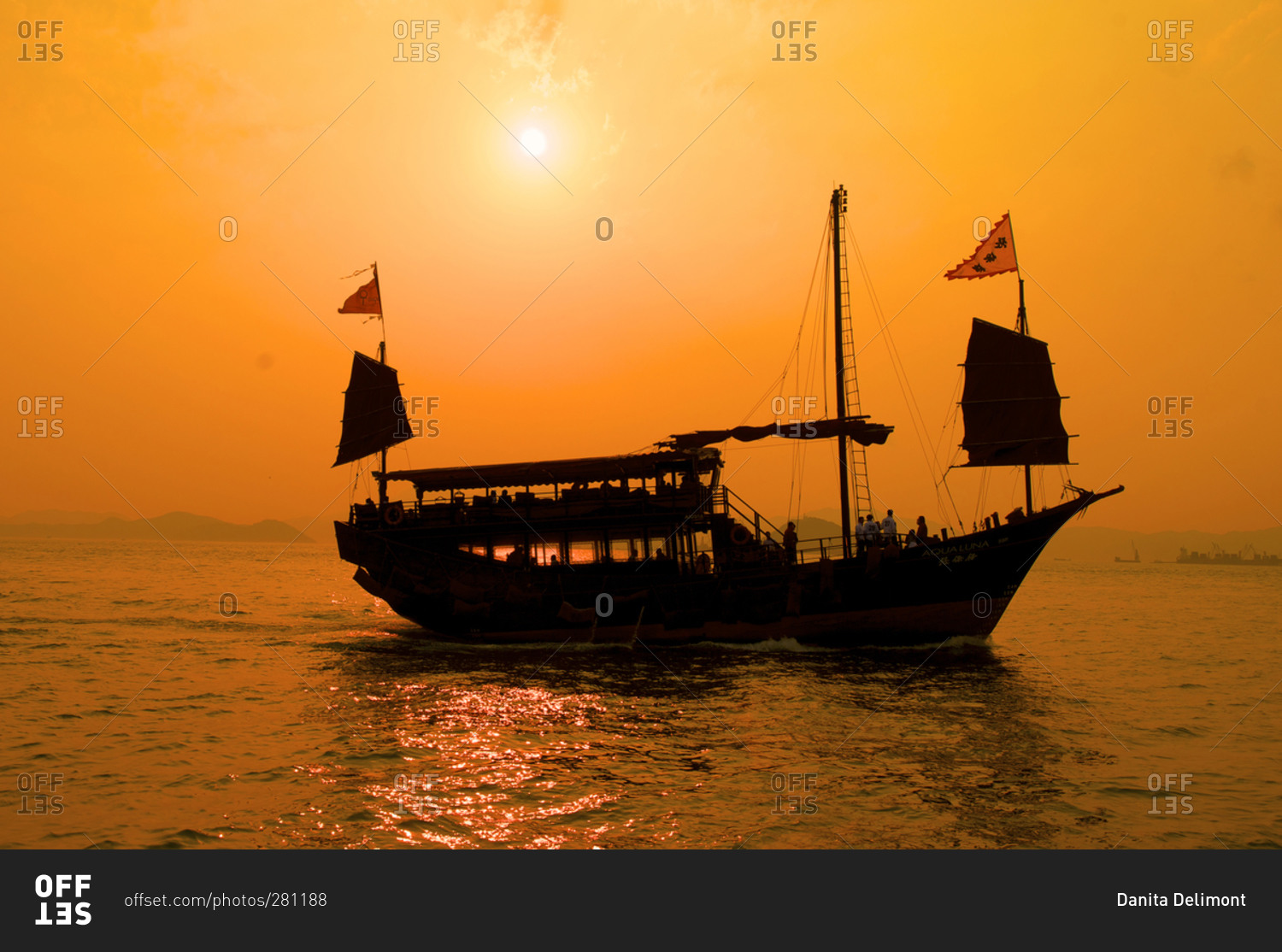 A junk sails through Aberdeen harbor near Hong Kong at sunset, Hong Kong, China