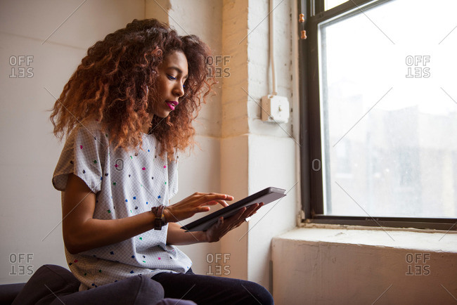 African American woman in loft looking at a tablet