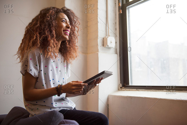 African American woman in loft smiling with a tablet