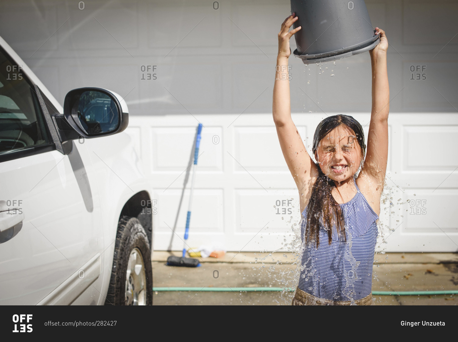 Girl dumping bucket of water on herself stock photo OFFSET