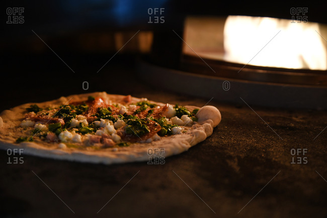 A pizza cooking in wood fired oven