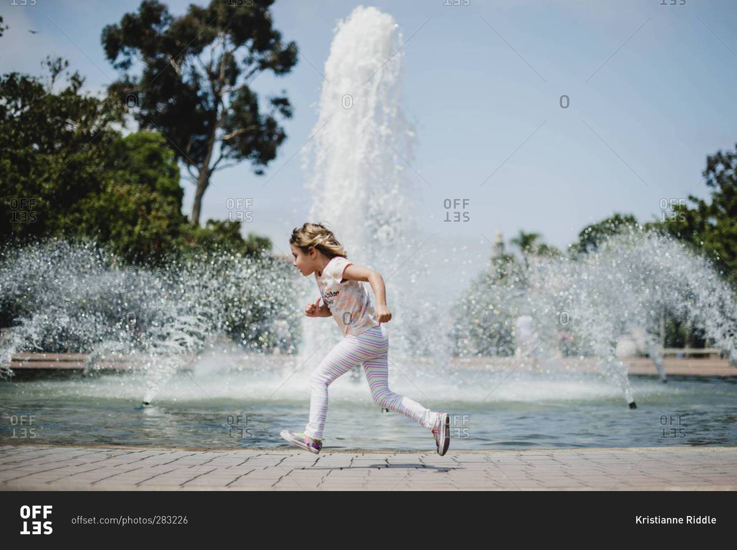Young girl running around fountain