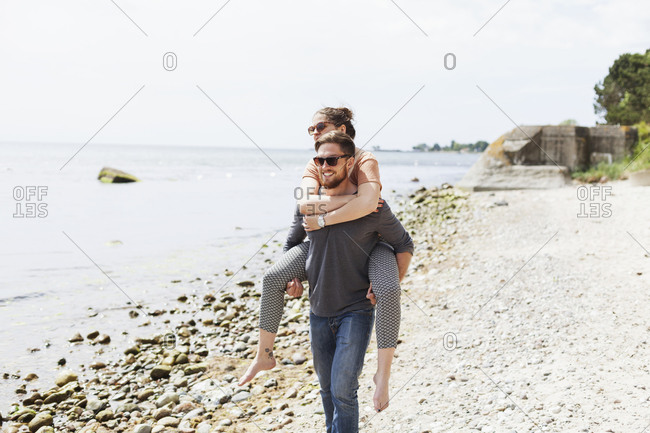 Man giving to girlfriend piggyback ride Stock Photo by ©gstockstudio  147713371