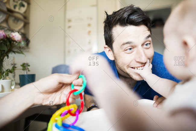 Baby girl sitting in a high chair playing with her dads
