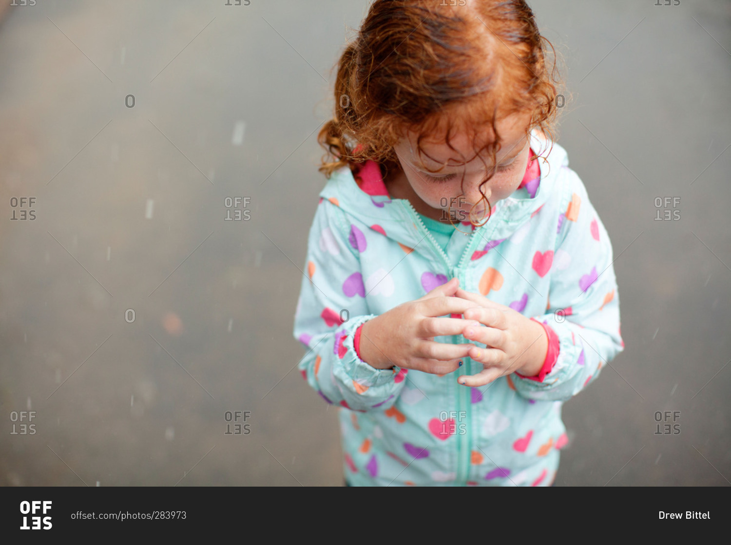Girl in raincoat standing in rain drops