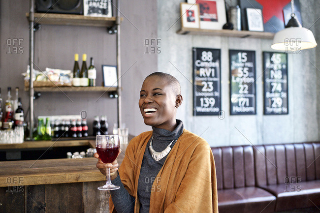 Woman laughing holding wine glass in bar