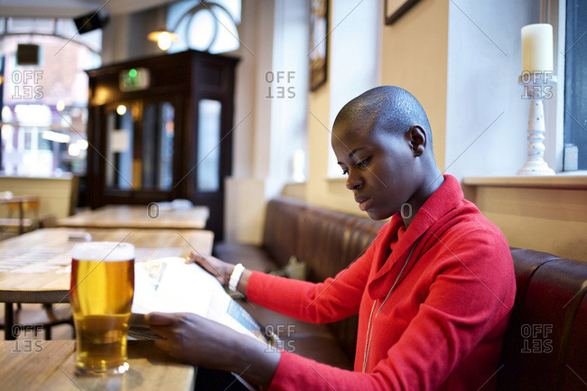 Woman reading a newspaper at a bar table