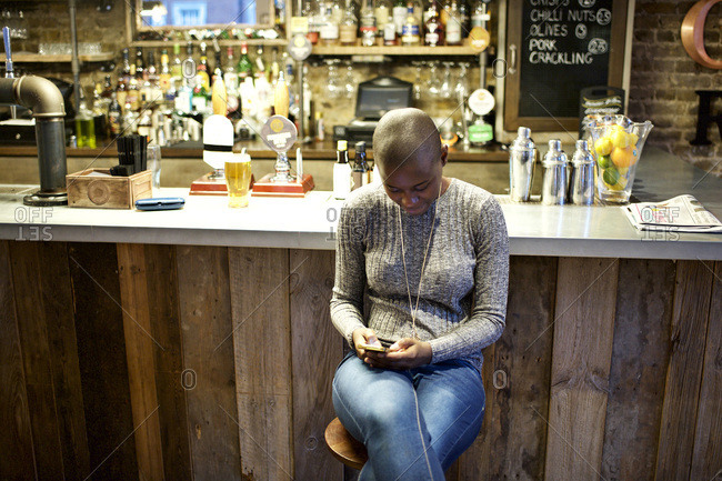 Young woman at a bar looking at phone